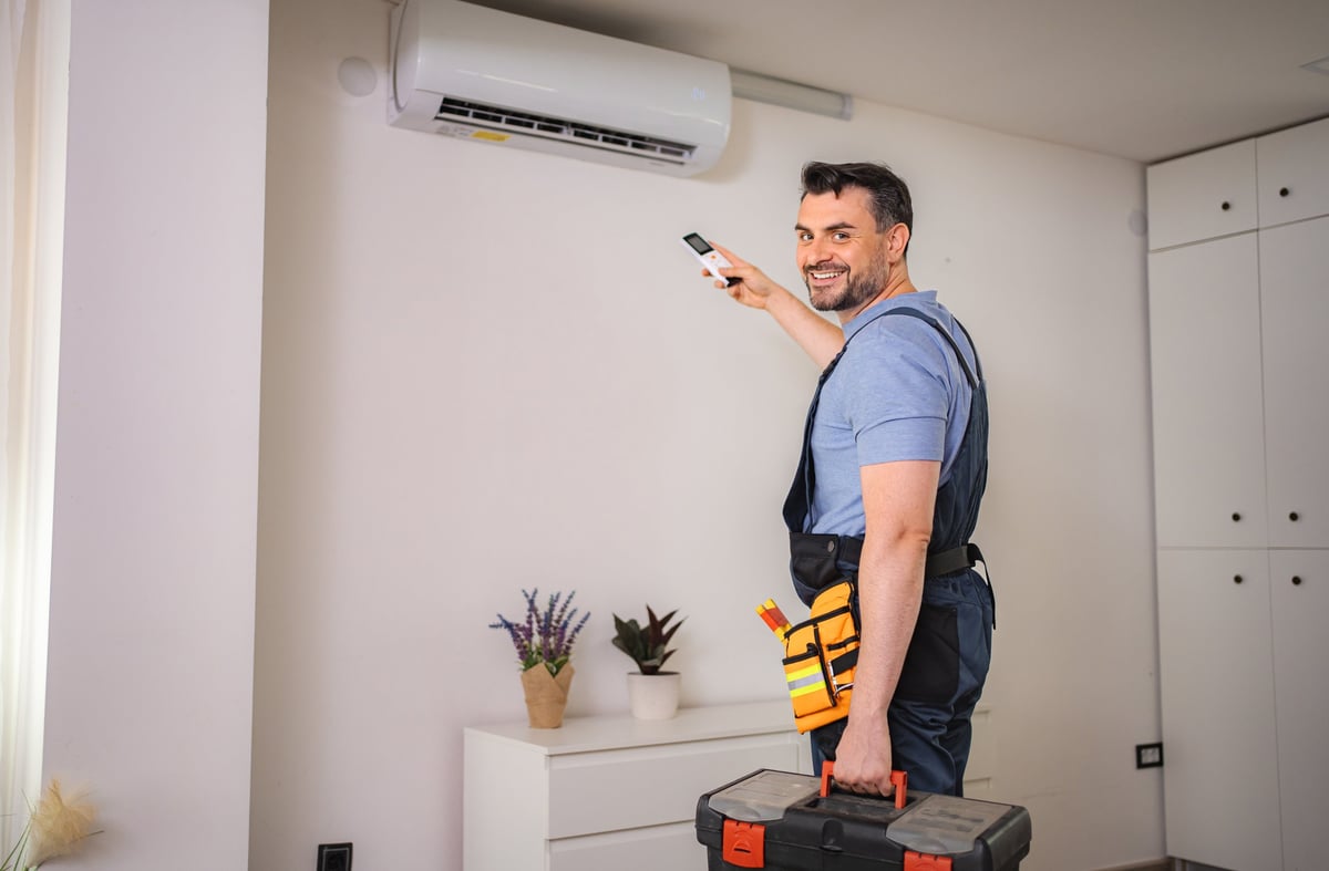 Technician installing air conditioner with remote